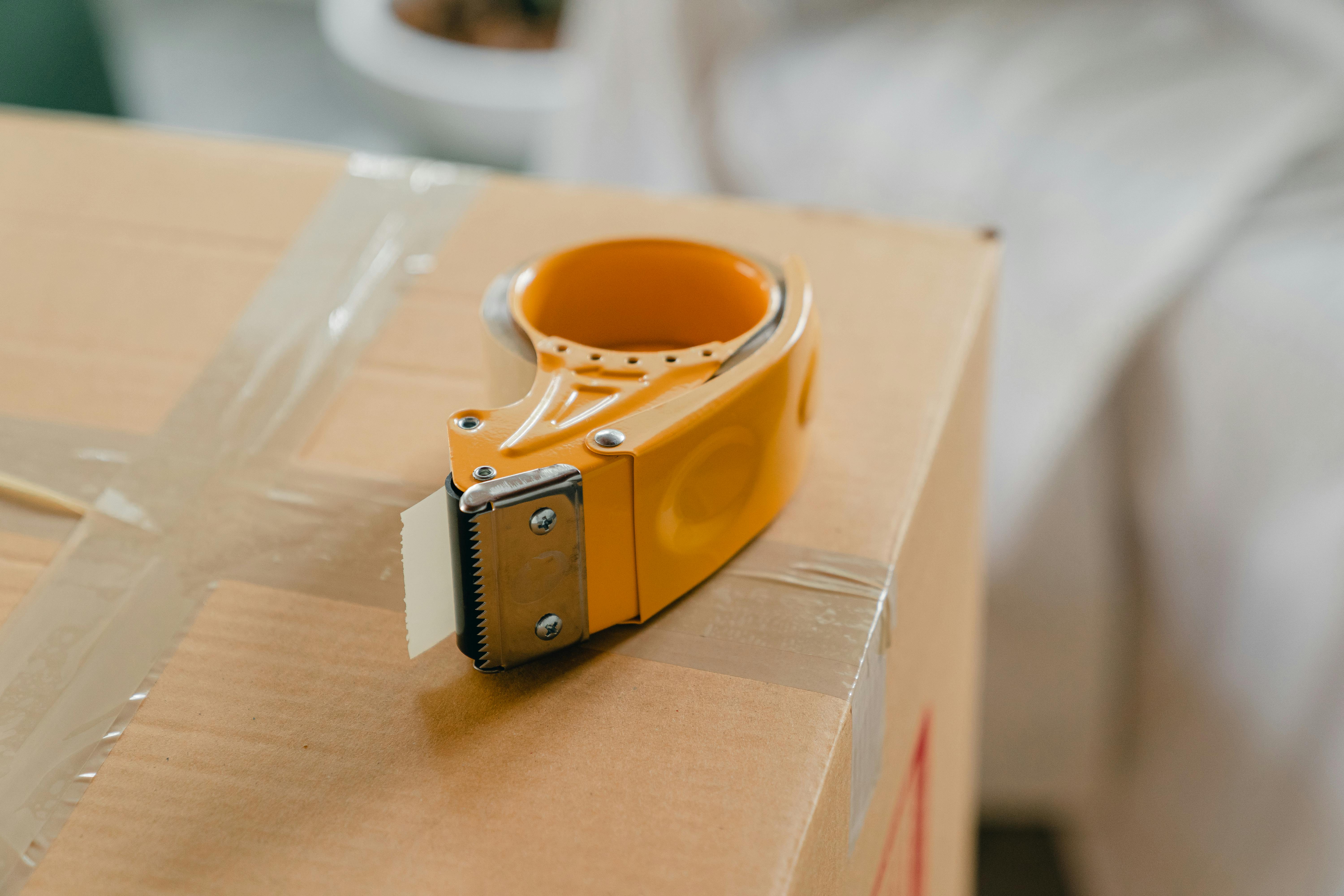 Packing tape dispenser resting on a sealed cardboard box ready for shipment.