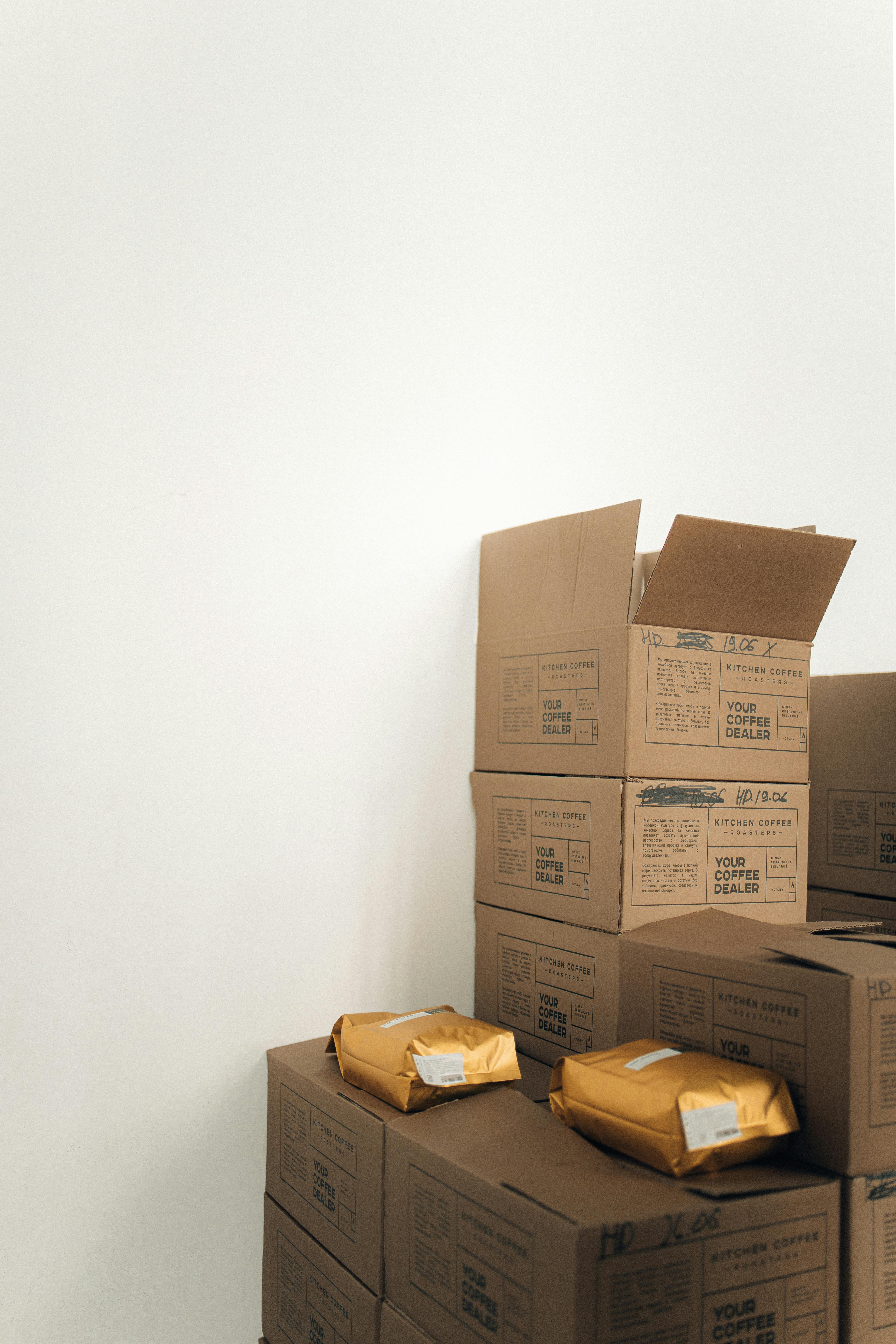 Stacked cardboard cartons and parcel envelopes arranged beside a warehouse wall.